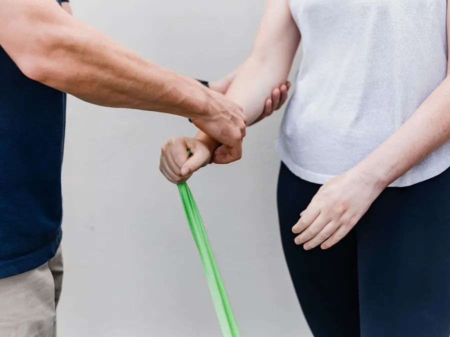 Exercício de ombro com faixa elástica, orientado pelo fisioterapeuta