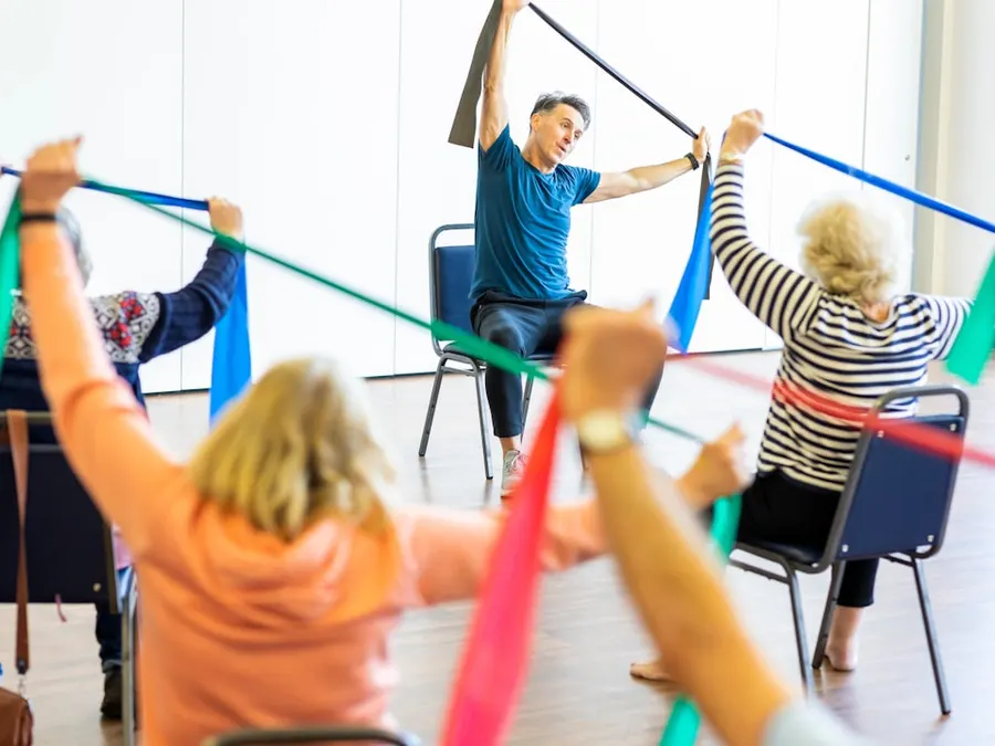 Turma de pessoas idosas em exercício com faixa elástica